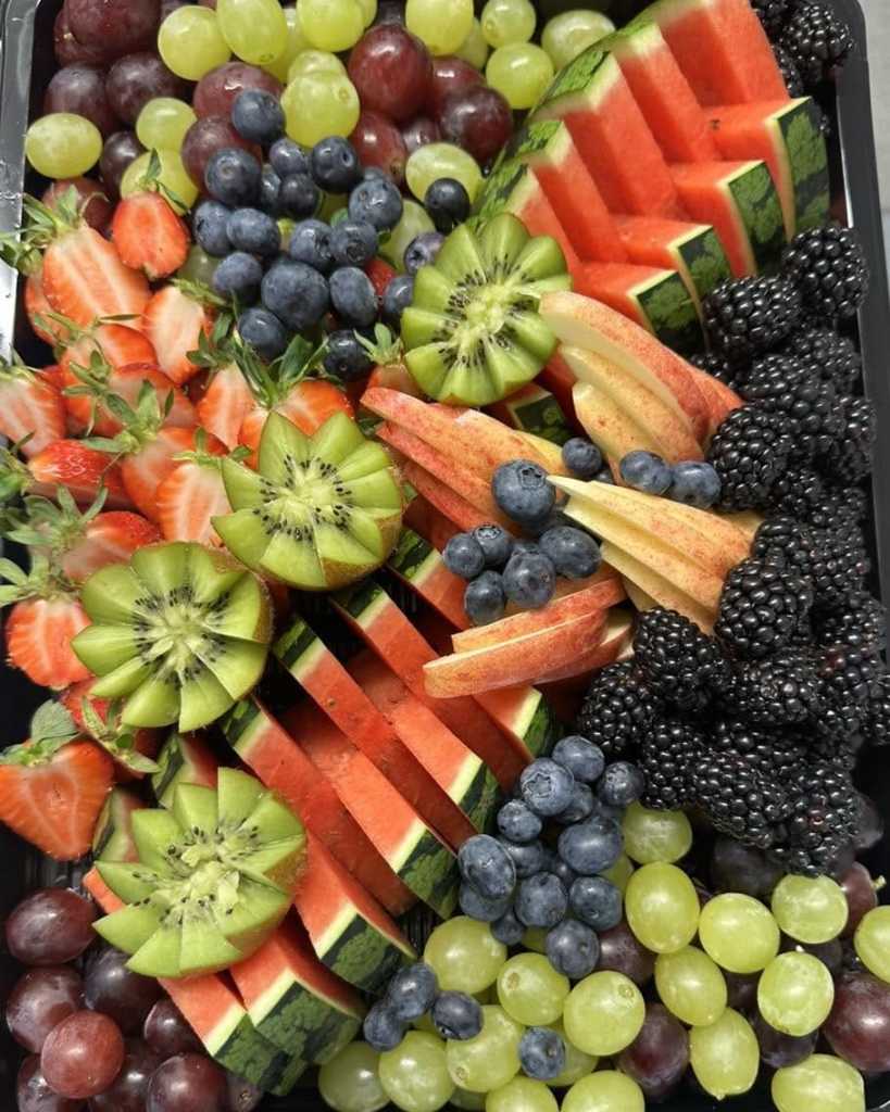 Platter of watermelon slices, kiwi, strawberries, apple, blueberries, blackberries and red and green grapes